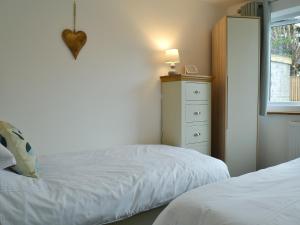 a bedroom with two beds and a dresser and a window at Lle Clyd in Harlech +4 photos