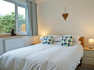 a bedroom with a white bed with blue pillows and a window at Lle Clyd in Harlech