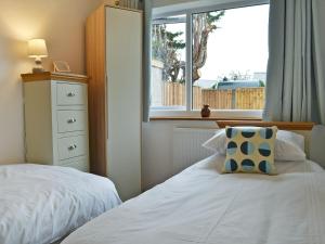 a bedroom with a white bed and a window at Lle Clyd in Harlech