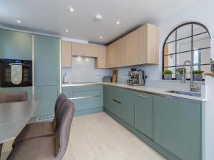 a kitchen with blue cabinets and a table and chairs at Olive Breeze in Felixstowe +11 photos