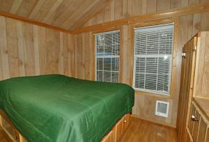 1 dormitorio con 1 cama verde en una habitación de madera en Arrowhead Camping Resort Deluxe Cabin 4 en Douglas Center
