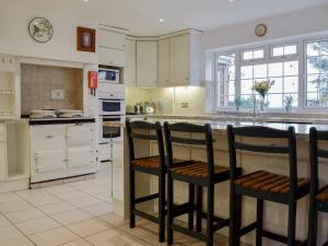 a kitchen with white cabinets and black bar stools at New Inn House in Harvington