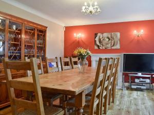 a dining room with a wooden table and a television at New Inn House in Harvington +19 photos