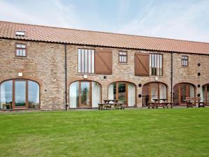 a brick building with picnic tables in the grass at Rievaulx Cottage in Filey +3 photos