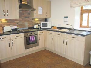 a kitchen with wooden cabinets and a sink and a microwave at Rievaulx Cottage in Filey