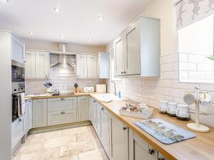 a kitchen with white cabinets and a wooden counter top at Water's Edge - Uk32390 in Dunford Bridge +15 photos