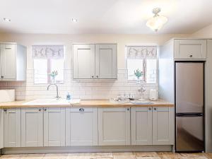 a kitchen with white cabinets and a sink at Water's Edge - Uk32390 in Dunford Bridge