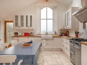 a kitchen with white cabinets and a table with a blue and white table cloth at Hopewell Barn in Hewelsfield