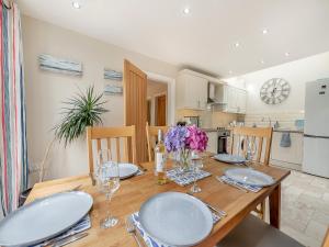a dining room table with chairs and a kitchen at Windsmoor Cottage On Gower in Penrice