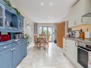 a kitchen with blue cabinets and a table with chairs at Windsmoor Cottage On Gower in Penrice