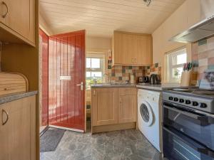 a kitchen with a stove and a washer and dryer at Rowan Cottage - Uk38991 in Dalcross
