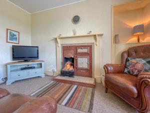 a living room with a fireplace and a television at Rowan Cottage - Uk38991 in Dalcross