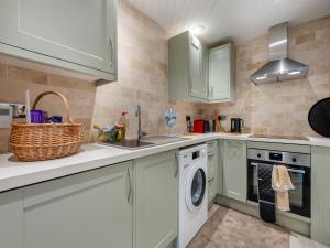 a kitchen with white cabinets and a washing machine at The Loft House in Canford Magna