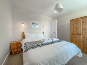 a bedroom with a large white bed and a wooden cabinet at Rowan Cottage - Uk38991 in Dalcross