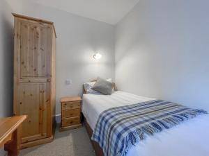 a small bedroom with a bed and a wooden cabinet at Rowan Cottage - Uk38991 in Dalcross +2 photos