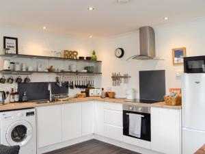 a kitchen with white cabinets and a washer and dryer at The Rest in St. Andrews