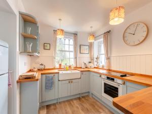 a kitchen with white cabinets and a clock on the wall at Cliff House in Beesands