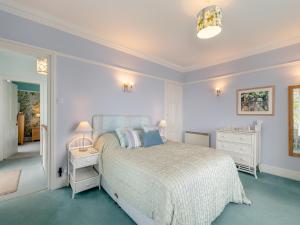 a white bedroom with a bed and a night stand at Cliff House in Beesands +13 photos