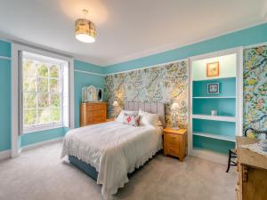 a bedroom with blue walls and a bed and a window at Cliff House in Beesands