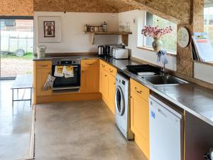 a kitchen with yellow cabinets and a washer and dryer at The Organic Cabin - Uk42325 in Horsington