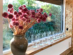 a vase with flowers sitting on a window sill with glasses at The Organic Cabin - Uk42325 in Horsington