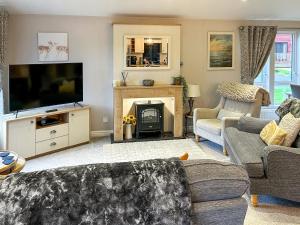 a living room with a television and a fireplace at Chatsworth Lodge - Uk50983 in Felton