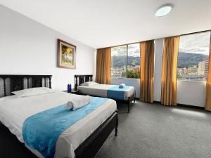 a hotel room with two beds and a large window at Hotel Santamaria en quito in Quito