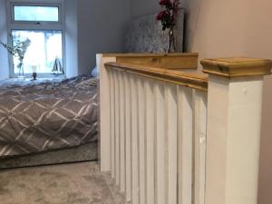 a bedroom with a bed and a white fence at Copper Crab Cottage in Amlwch
