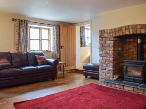 a living room with a couch and a brick fireplace at Colstey Farmhouse in Acton