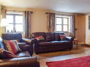 a living room with a leather couch and two chairs at Colstey Farmhouse in Acton