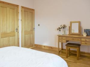 a bedroom with a bed and a desk with a mirror at Tan-Y-Derwwen in Mydroilin