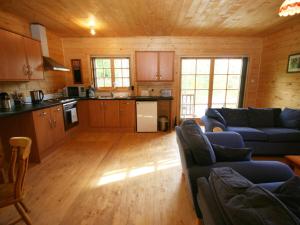 a living room with couches and a kitchen at Auchenhill Lodge in Lochend