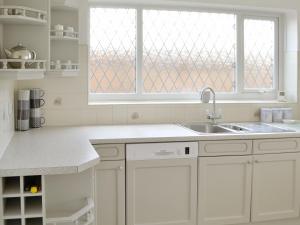 a white kitchen with a sink and a window at Dunpullin in Bedlington