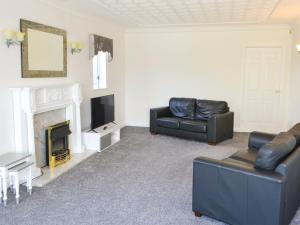 a living room with two leather couches and a fireplace at Dunpullin in Bedlington