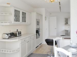 a kitchen with white cabinets and a table and chairs at Dunpullin in Bedlington