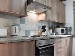 a kitchen with wooden cabinets and a stove top oven at Maple - Uk5501 in Killin