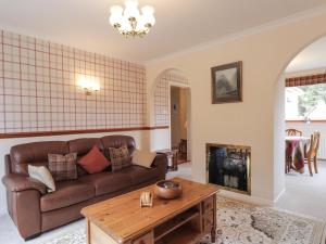 a living room with a couch and a fireplace at Holly Cottage in Gorstan