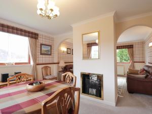 a living room with a table and a fireplace at Holly Cottage in Gorstan