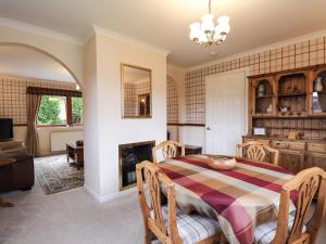 a dining room with a table and a fireplace at Holly Cottage in Gorstan