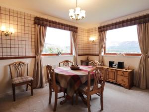 a dining room with a table and chairs and two windows at Holly Cottage in Gorstan +27 photos