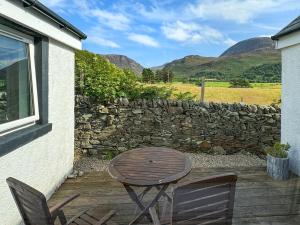 a patio with a table and chairs and a stone wall at The Green in Lochranza