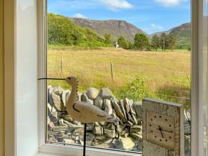 a statue of a bird on a window with a clock at The Green in Lochranza