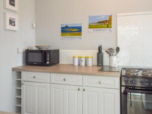 a kitchen with white cabinets and a black microwave at Seacliffe in Kildonan +8 photos