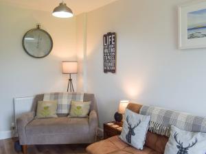 a living room with a couch and a clock on the wall at Seacliffe in Kildonan
