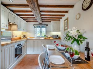a kitchen with white cabinets and a table with wine glasses at Swallow Cottages, No 2 - Uk46810 in Thurgarton