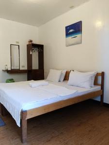 a large bed with white sheets and pillows on it at Elsa's beach house in Itaytay