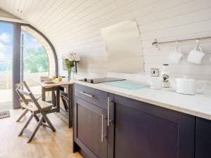 a kitchen with a counter and a table with a chair at Gwennol- Uk37573 in Llanboidy