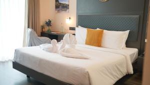 a bedroom with a large white bed with towels on it at Surf and Sand in Candolim