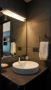 a bathroom with a white sink and a mirror at Surf and Sand in Candolim