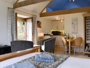 a bedroom with a bed and a kitchen with a table at Tamar Orchard Barn in Gunnislake